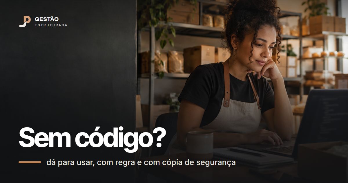 Dona de loja de avental olhando o notebook numa mesa de escritório nos fundos da loja, com caixas de estoque atrás