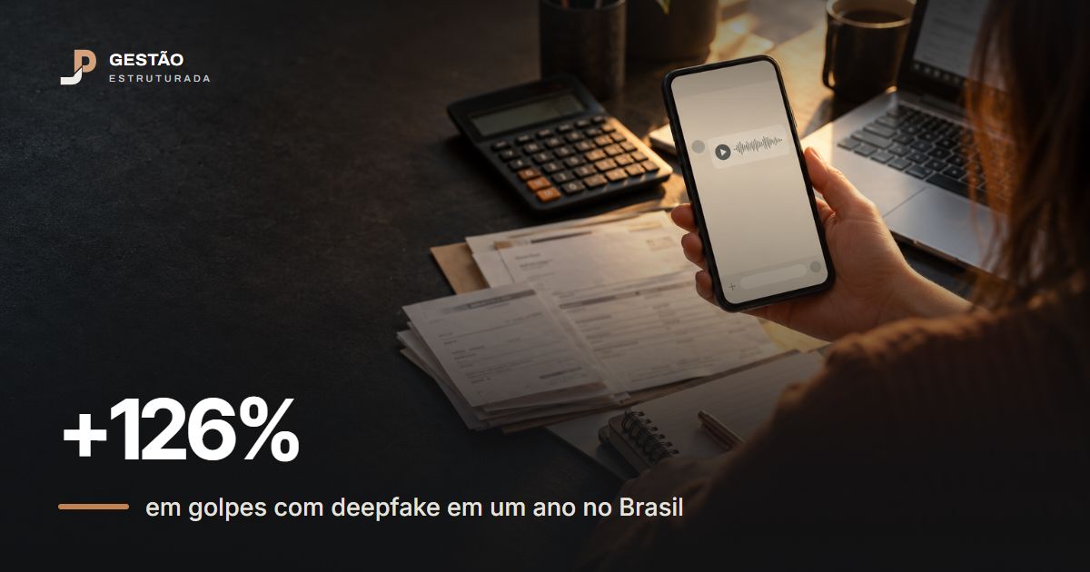 Pessoa do financeiro segurando o celular com uma mensagem de voz na tela, ao lado de notas e calculadora